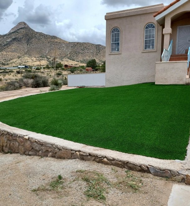 Front-yard artificial turf installation framed by a stone retaining wall