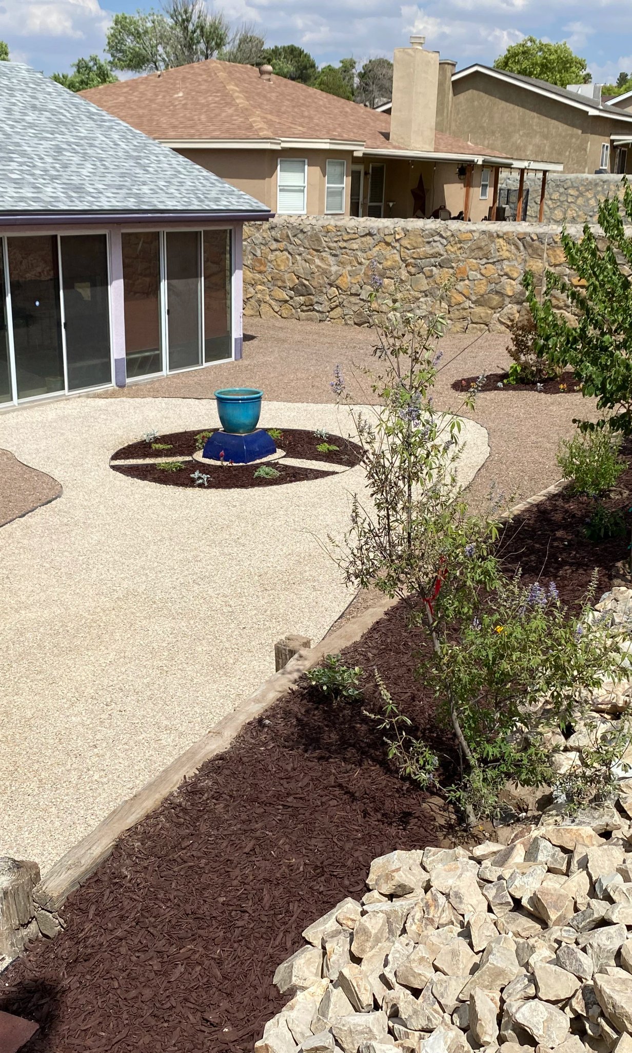 Raised stone bed planted with desert-adapted shrubs by Brainard's Greenscapes in Las Cruces