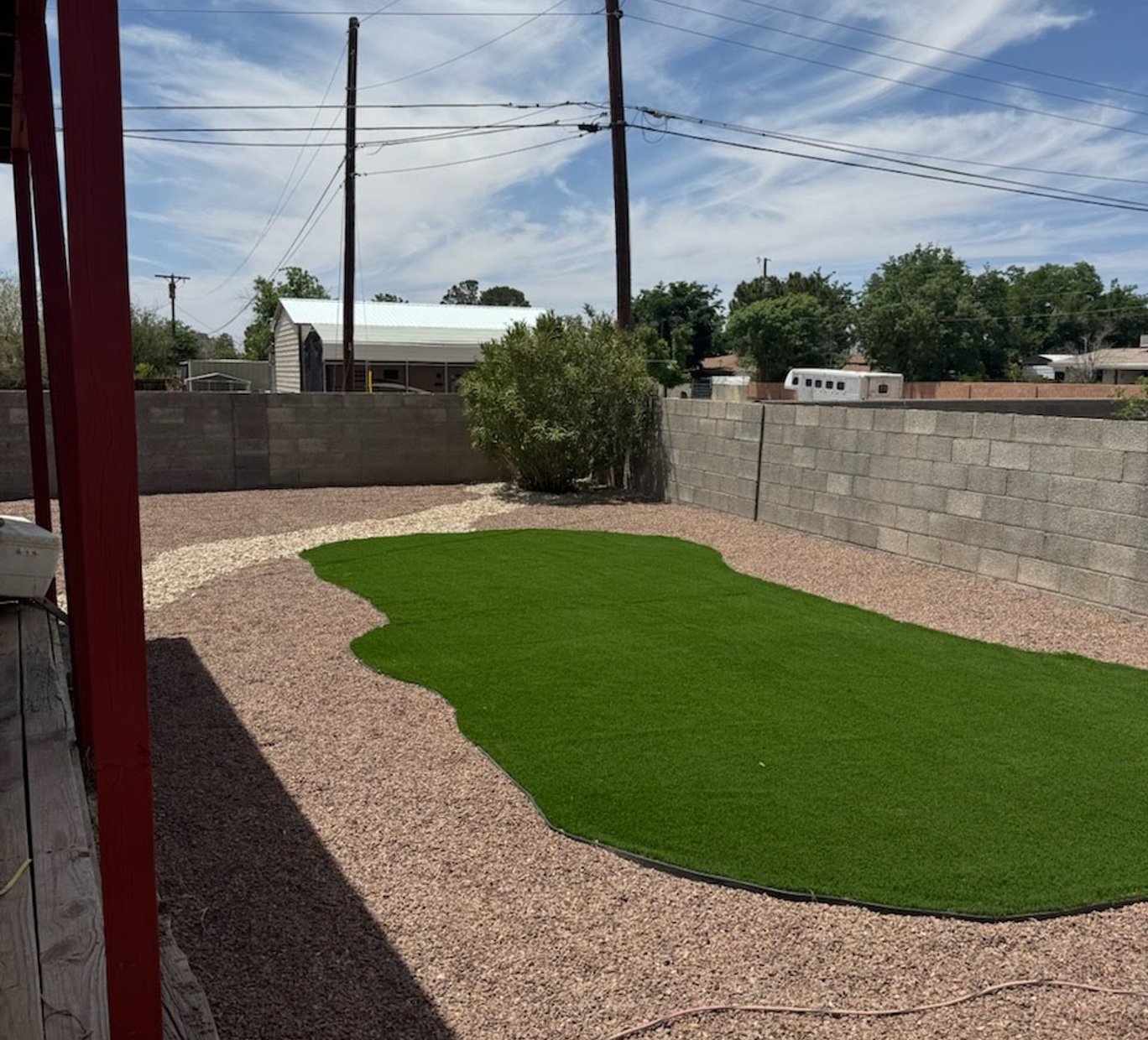 After: backyard with newly installed artificial turf and clean gravel borders