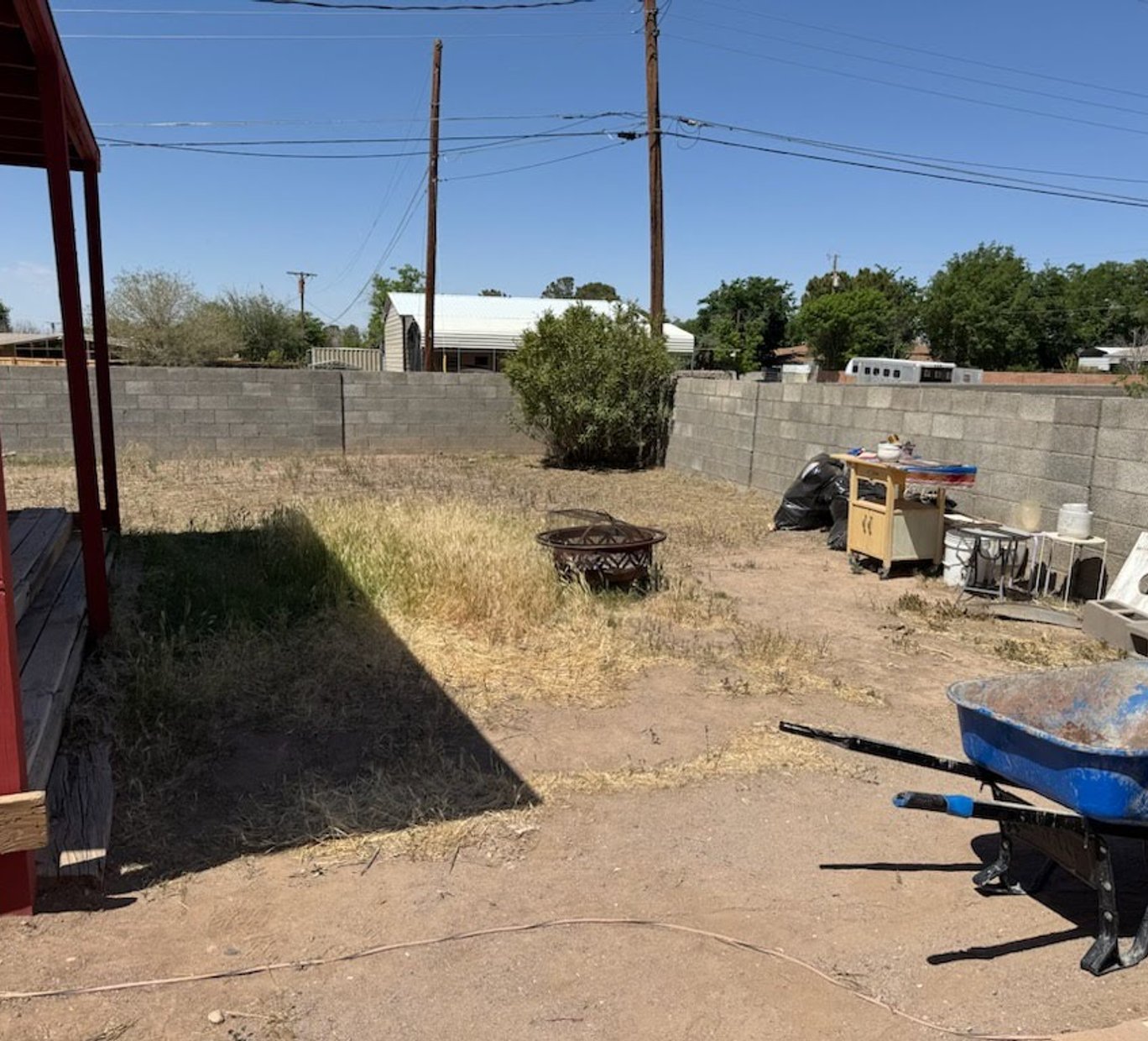 Before: bare backyard with dirt, weeds, and debris prior to landscaping