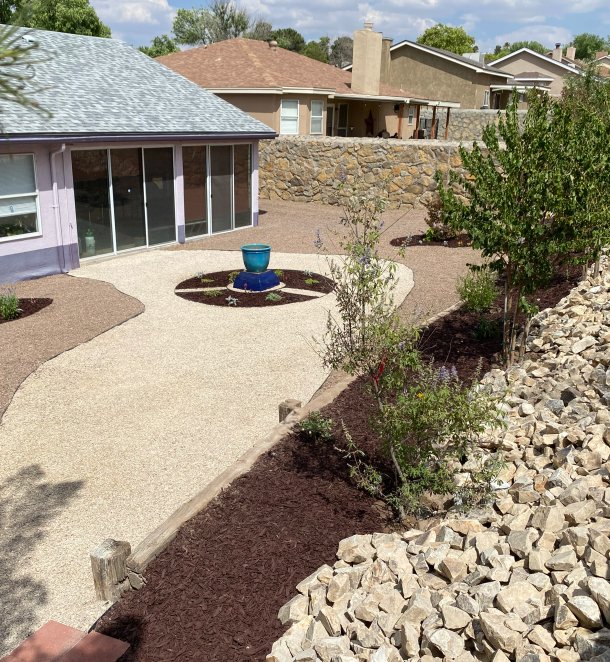 Courtyard xeriscape with circular gravel patterns and a blue water feature