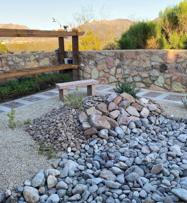 Backyard xeriscape with stacked-rock beds and stone bench overlooking the Las Cruces mountains